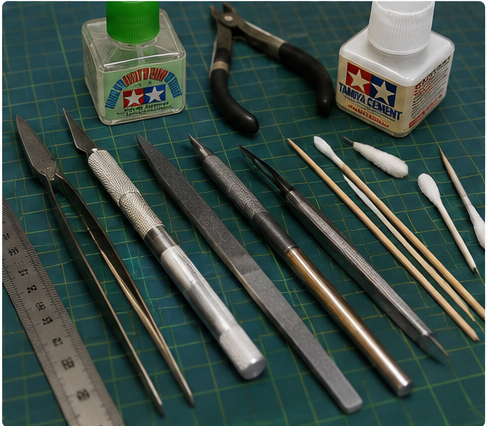 Essential Tools and Techniques — Tamiya cement, sprue cutters, hobby knife, tweezers, and sanding tools on a cutting mat