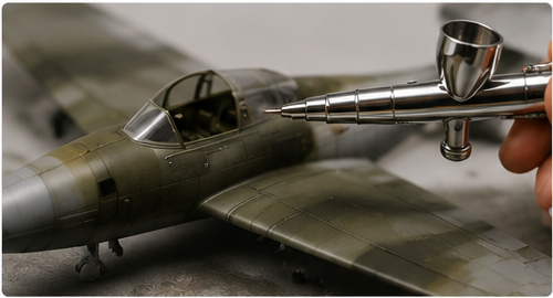 Airbrush applying paint to a scale model aircraft